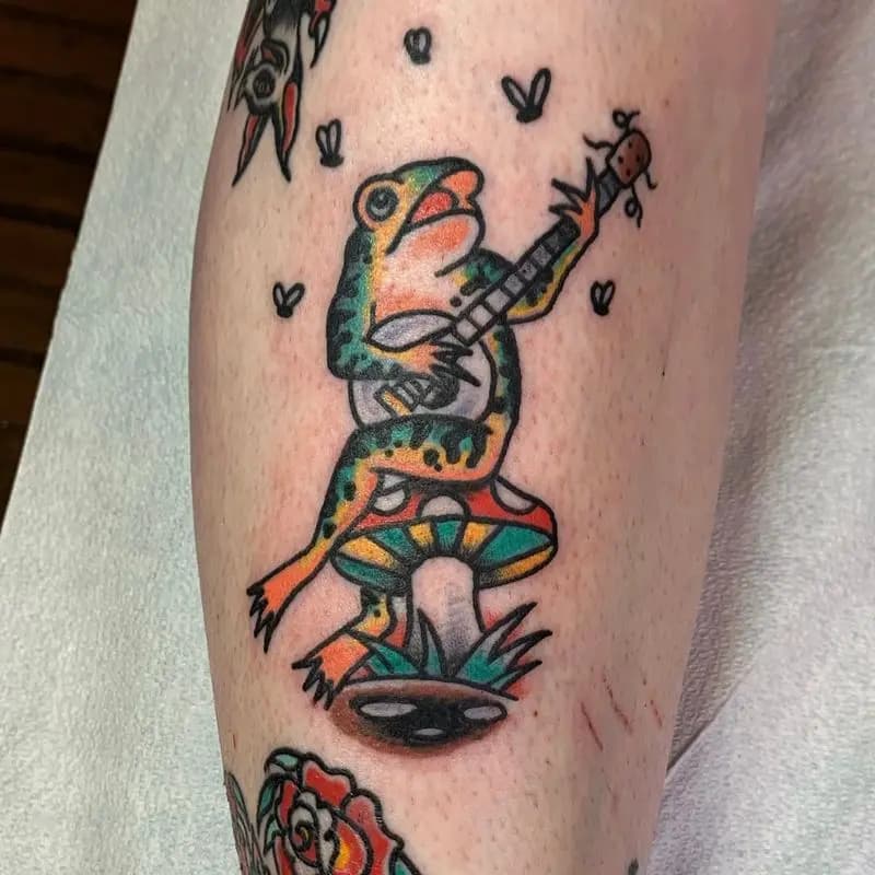 a frog tattoo holding a guitar